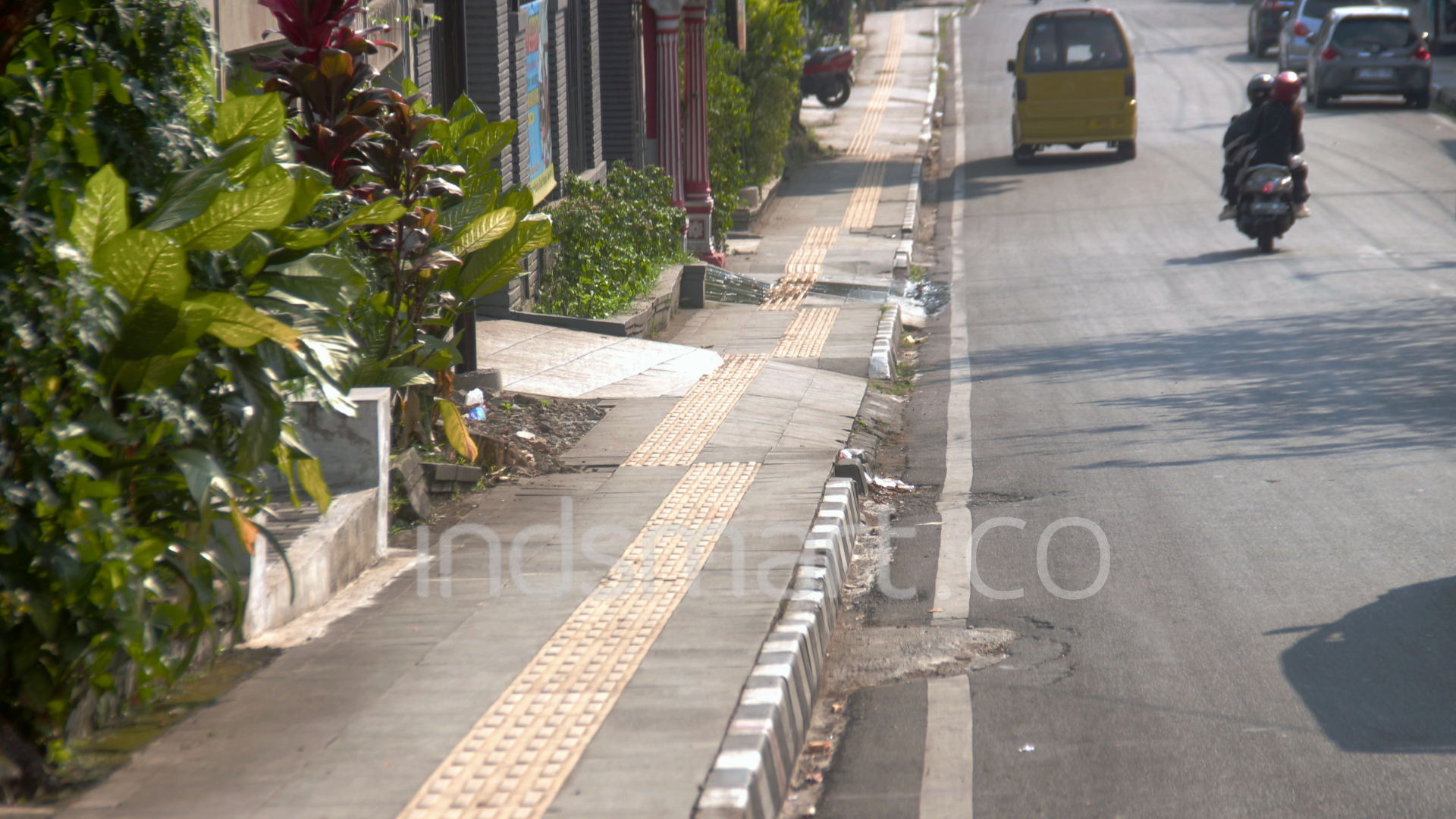 Sejumlah ubin kuning jalur pemandu (guiding block) di sepanjang trotoar Jalan Arif Rahman Hakim menuju Kantor Dinas Perhubungan Kota Sukabumi terpasang tidak lurus dan berkelok-kelok. Tata kelola infrastruktur yang semrawut ini dinilai mengabaikan aspek keselamatan dan berubah menjadi labirin berbahaya bagi pejalan kaki penyandang disabilitas netra yang melintas di kawasan tersebut. (Foto: Indsmart.co/Rizal Fahrudin)